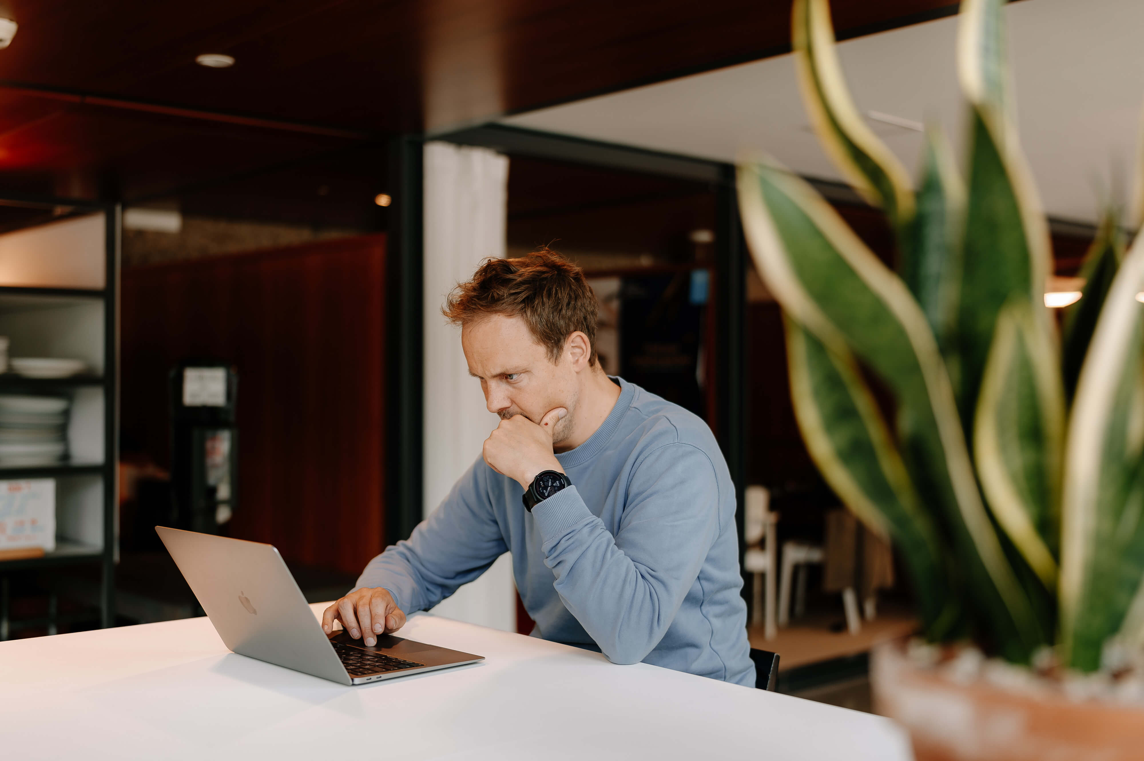Man working on his laptop at a table in a bright office